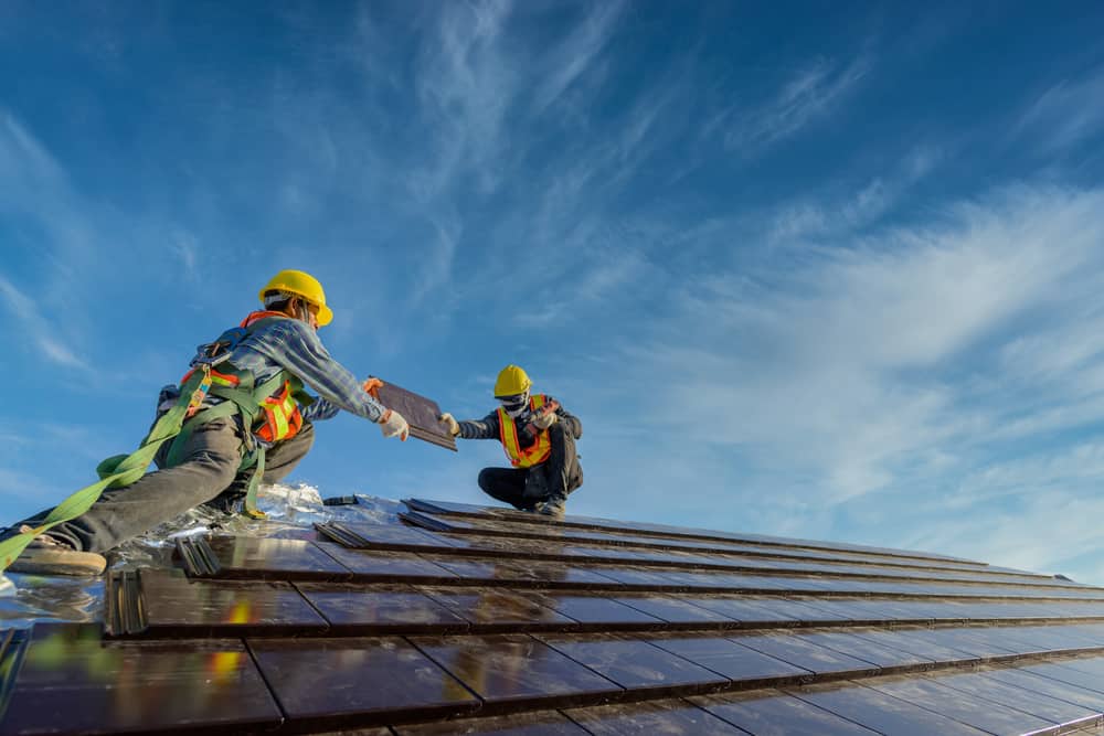 Two Roofers Wearing Safety Clothing and Working As A Team